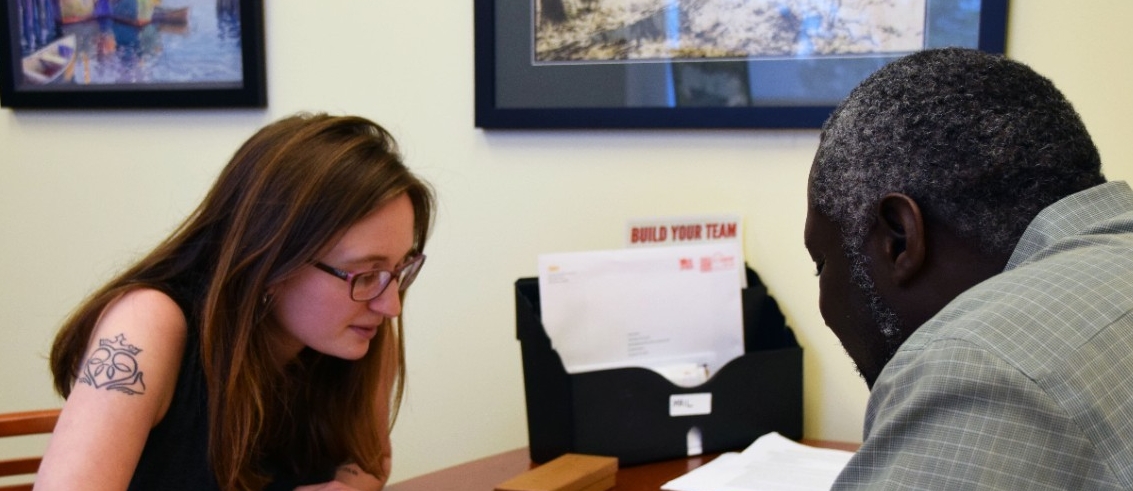 A student and a professor sit together at a table for a conversation. 