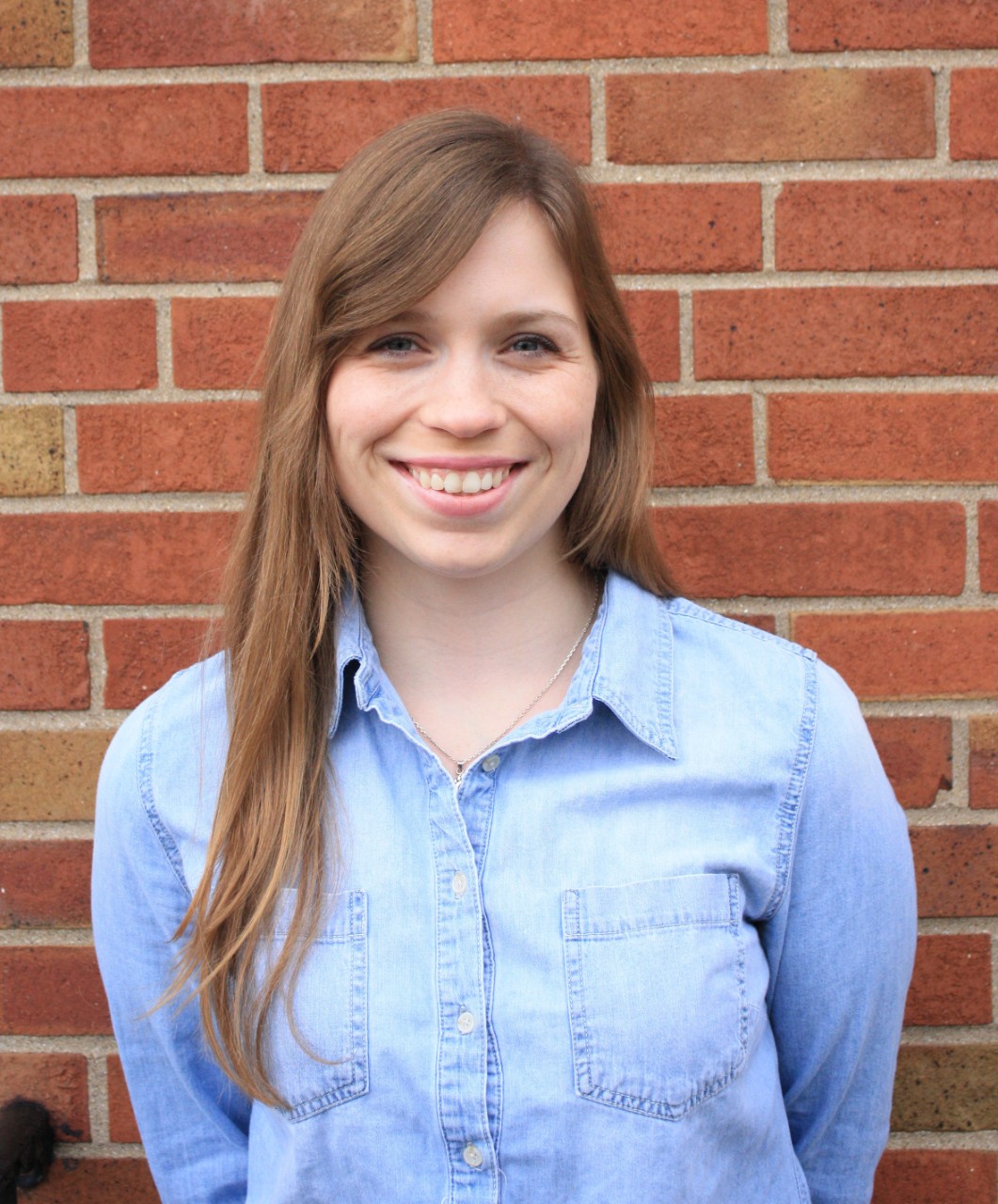 Casual headshot of Kendra Leahy standing against a brick wall.