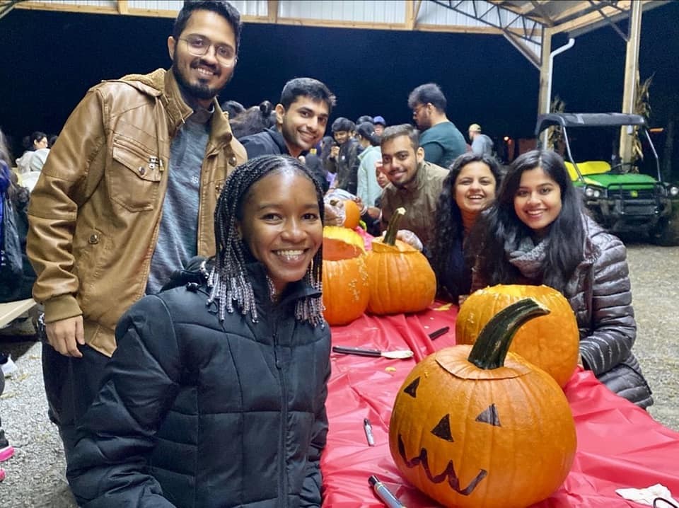 Graduate students pose with carved and decorated pumpkins. 